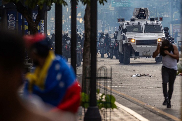 Manifestantes corren durante enfrentamientos entre opositores y miembros de la Guardia Nacional Bolivariana (GNB), por los resultados de las elecciones presidenciales este lunes, en Caracas (Venezuela). Foto EFE