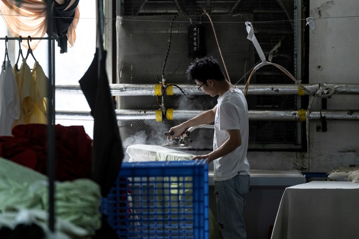 Un trabajador plancha tela en una fábrica de ropa de Guangzhou, China, el miércoles 9 de abril de 2025. Las pequeñas fábricas orientadas a la exportación con márgenes de beneficio ínfimos han desempeñado un papel fundamental en la competitividad internacional de China. Muchas se enfrentan ahora al desastre. (Qilai Shen/The New York Times)