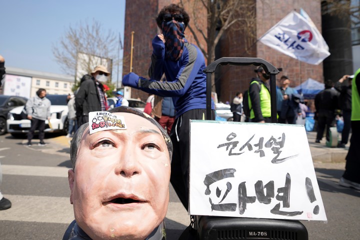 Un hombre baila cerca de una efigie que representa al destituido presidente surcoreano Yoon Suk Yeol tras la destitución de Yoon, cerca del Tribunal Constitucional en Seúl, Corea del Sur, el viernes 4 de abril de 2025. En las letras se lee "Yoon Suk Yeol expulsado". (AP Photo/Lee Jin-man)