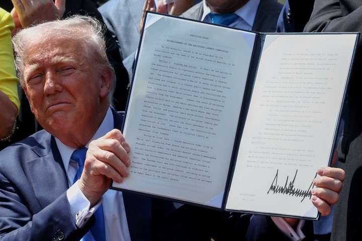 El presidente de Estados Unidos, Donald Trump, sostiene una orden ejecutiva firmada sobre el "Establecimiento de la Comisión de Libertad Religiosa", rodeado de líderes religiosos, durante el Día Nacional de Oración, en el Jardín de Rosas de la Casa Blanca. Foto Reuters