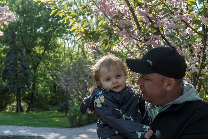 Oleksandr Polishchuk, de 46 años, con su hija Oleksandra, de 2, en un parque de Kiev, Ucrania, el 27 de abril de 2025. Un ataque con misiles rusos contra su edificio de apartamentos los dejó en un montón de escombros, pero con vida. (Brendan Hoffman/The New York Times)