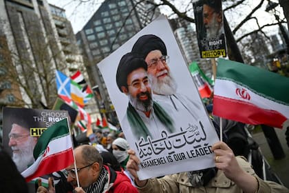 Un manifestante sostiene una pancarta con la imagen del difunto ayatolá Ali Khamenei (centro derecha) y del nuevo líder supremo de Irán, Mojtada Khamenei (centro izquierda), durante una protesta anual, este año estática, organizada por el grupo propalestino Al-Quds en el centro de Londres