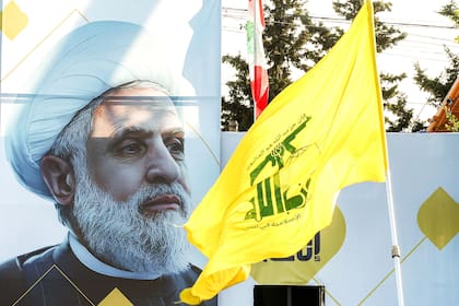 Una fotografía de Naim Qassem, líder del movimiento chií libanés Hezbollah, se exhibe cerca de la bandera amarilla del partido